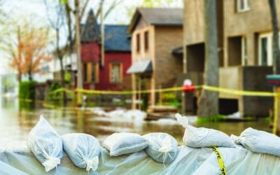 Close shot of flood Protection Sandbags with flooded homes in the background